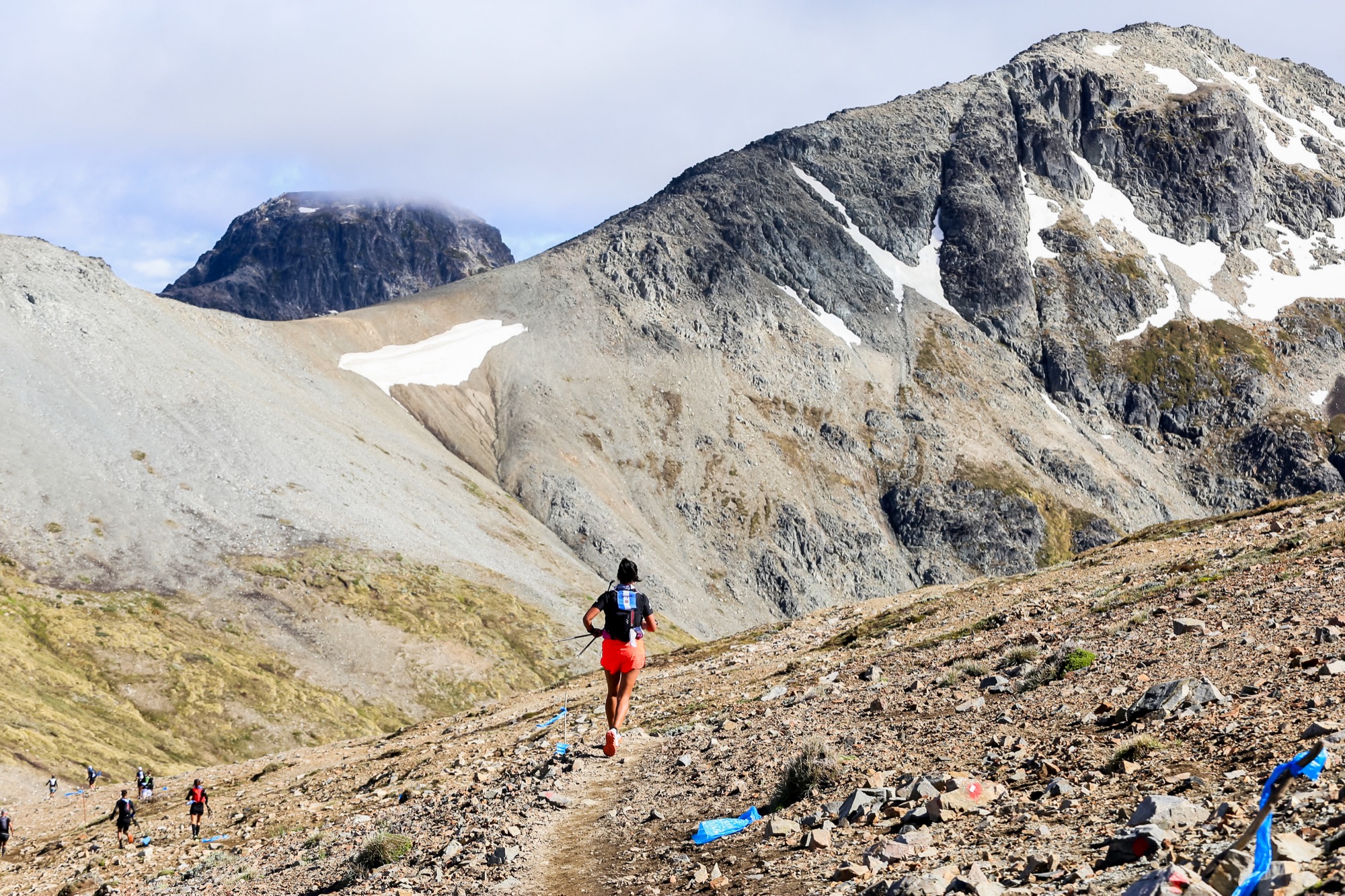 A runner moves alone along a high-mountain trail