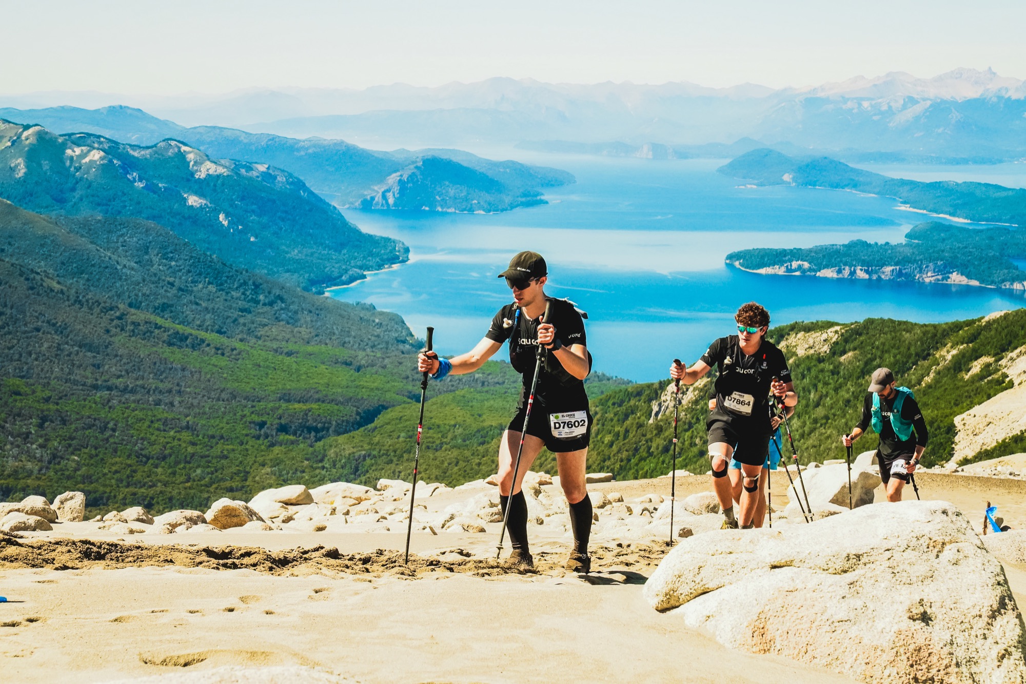 Runners moving along a ridge with the lake and the range in the background