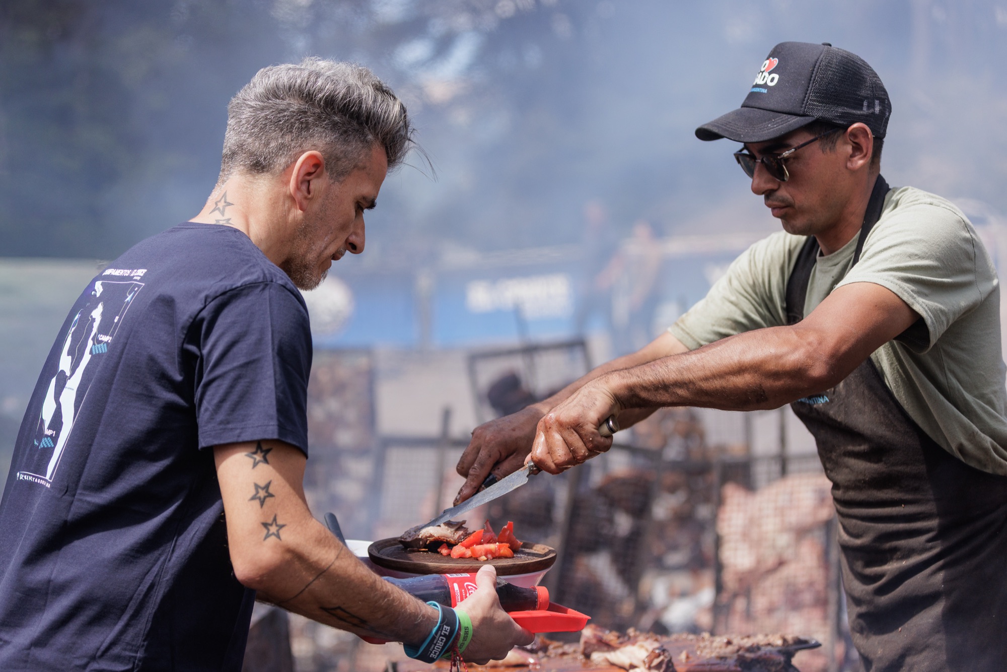 Dos integrantes del equipo cocinan a la parrilla en el campamento