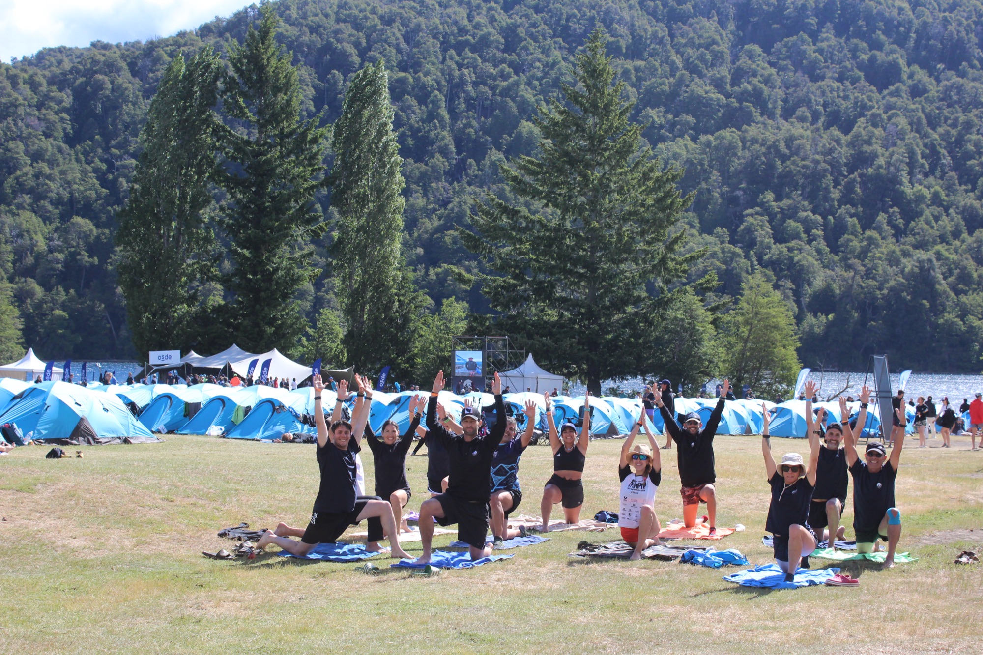 A group of runners stretching at the camp, with the tents behind them