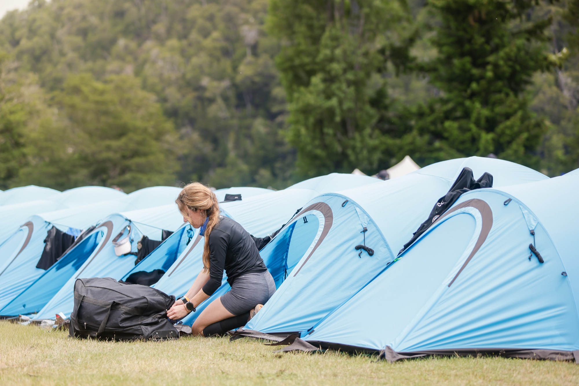 A runner arranges her things next to her blue tent
